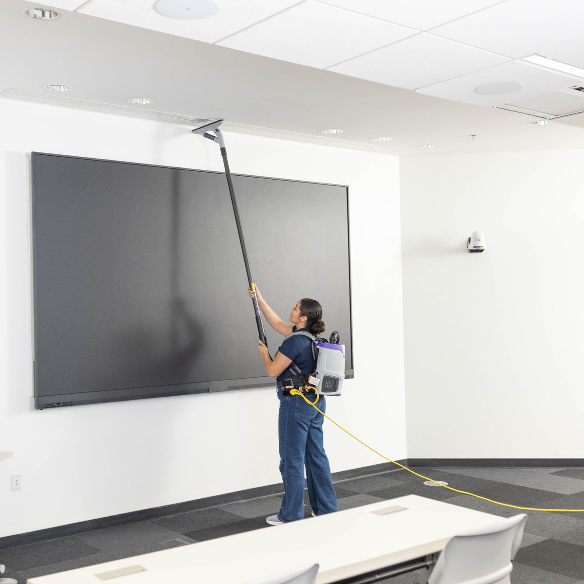 Cleaning the top of a wall display with the GoHigh ProBlade from the floor